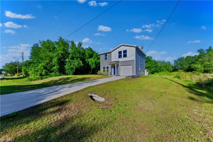 View of front of home with a front yard, driveway, and a garage