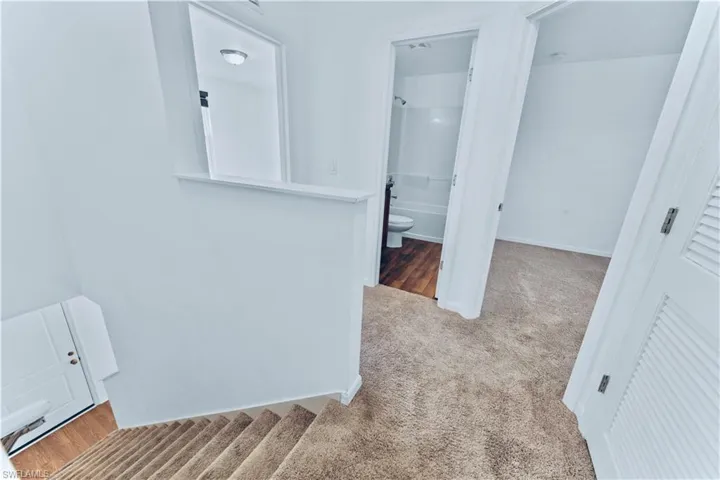 Corridor with carpet, baseboards, and an upstairs landing