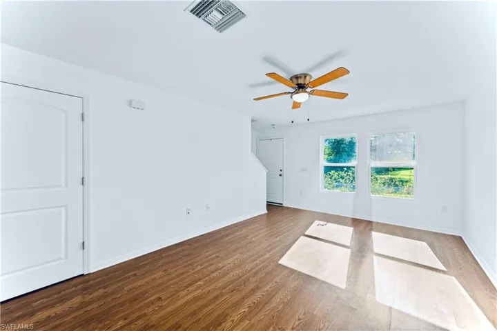 Spare room with wood finished floors, baseboards, a ceiling fan, and visible vents