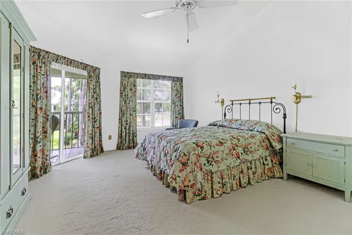 Carpeted bedroom with high vaulted ceiling, ceiling fan, and access to outside