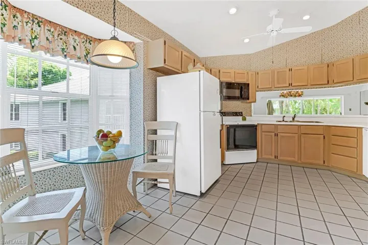 Kitchen with white appliances, a wealth of natural light, ceiling fan, and hanging light fixtures