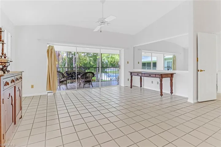 Tiled living room featuring ceiling fan and vaulted ceiling
