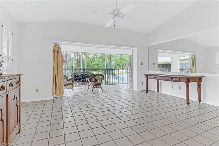 Living room featuring vaulted ceiling, ceiling fan, and light tile floors