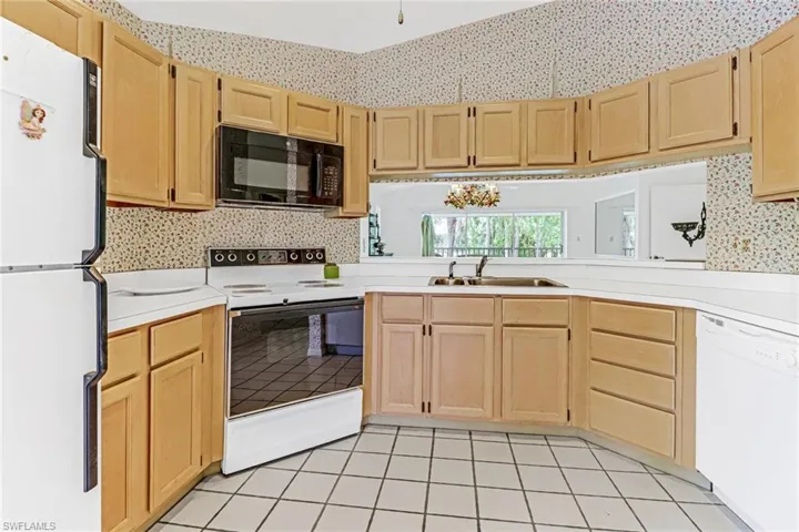 Kitchen with sink, light tile flooring, and white appliances