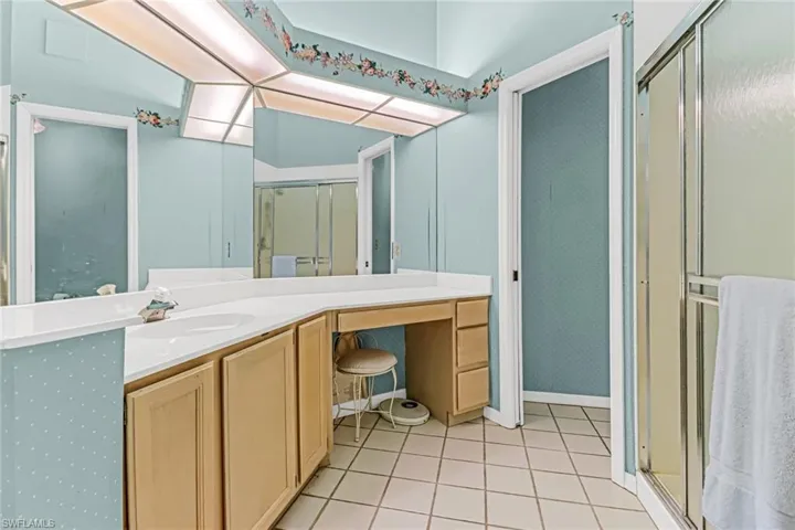 Bathroom with vanity with extensive cabinet space, tile floors, and a shower with door