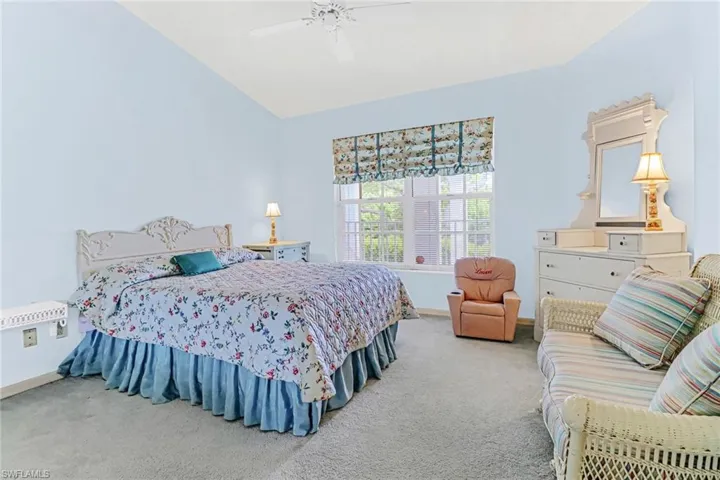 Carpeted bedroom featuring vaulted ceiling and ceiling fan
