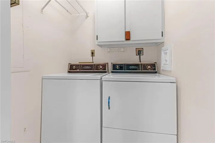 Clothes washing area with electric dryer hookup, washer and clothes dryer, and cabinets
