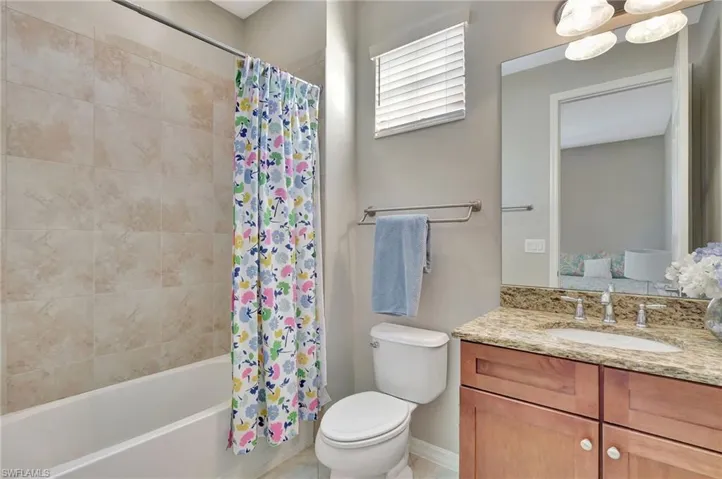 2nd ensuite full bathroom featuring vanity, an inviting chandelier, toilet, and shower / bathtub combination with curtain