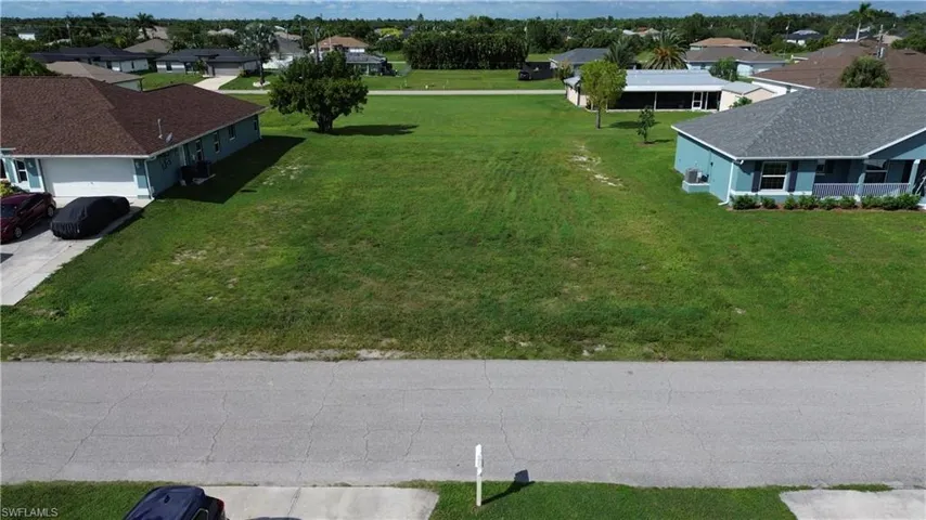 Expansive undeveloped lot featuring a grass expanse and a paved street frontage