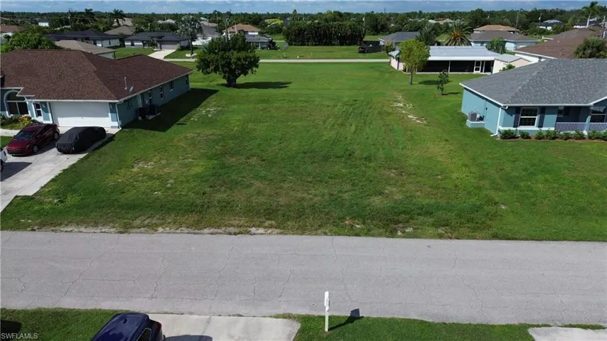 Expansive undeveloped lot featuring a grass surface and surrounding residential properties