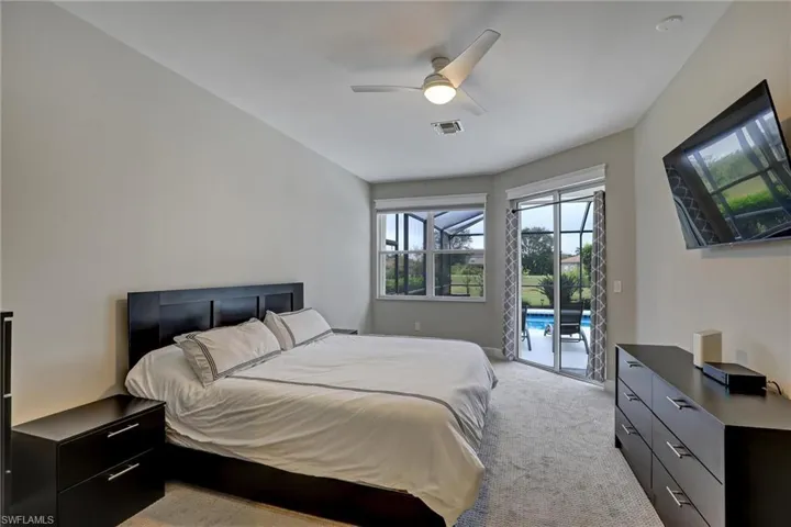 Bedroom featuring a vaulted ceiling with a ceiling fan, wall-mounted television, and direct outdoor access through sliding glass doors to a screened patio and pool area