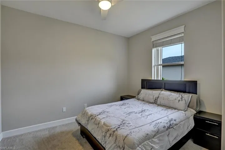 Carpeted room featuring a ceiling fan, a window with blinds, and white baseboards