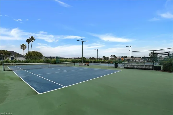 Tennis court with blue playing surface and green surrounds