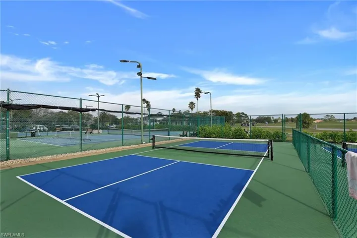 Multiple pickleball courts with blue playing surfaces and green surrounds