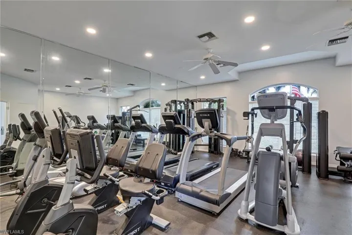 Dedicated fitness room featuring wall-to-wall mirrors, recessed lighting, and ceiling fans