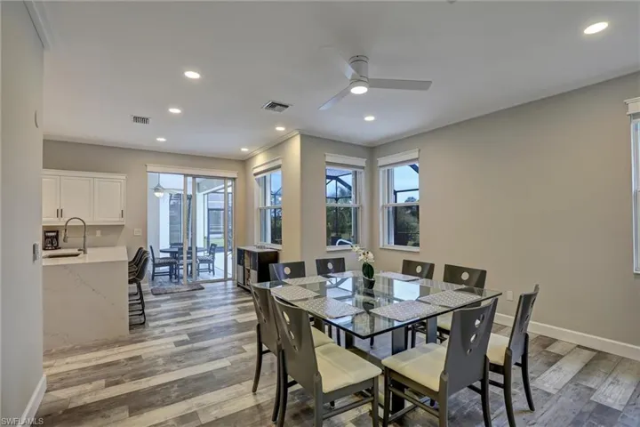 Open-concept dining and kitchen area featuring wood-finish flooring, recessed lighting, and a ceiling fan