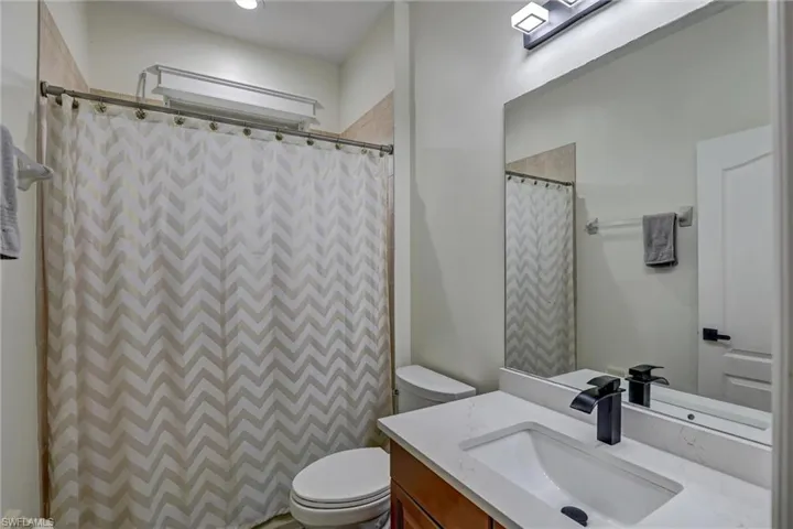 Bathroom featuring a vanity with a white rectangular sink, quartz countertop, and dark wood-finish cabinetry