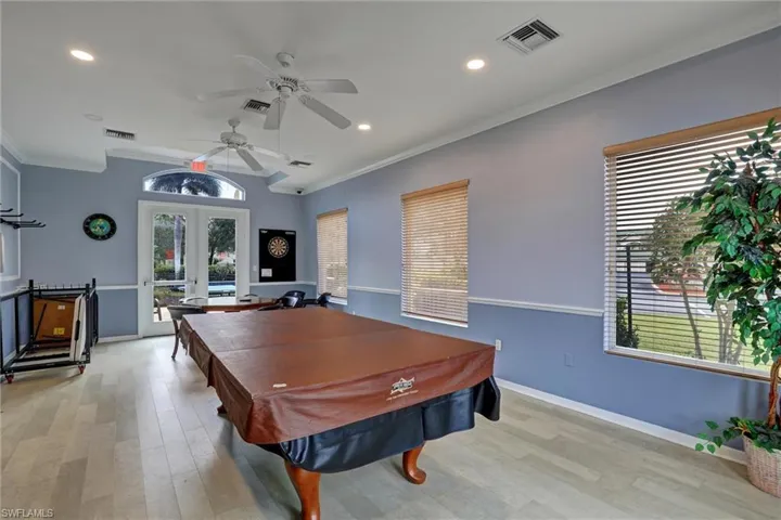 Open-concept room featuring light wood-finish flooring, two ceiling fans, recessed lighting, and multiple windows with blinds