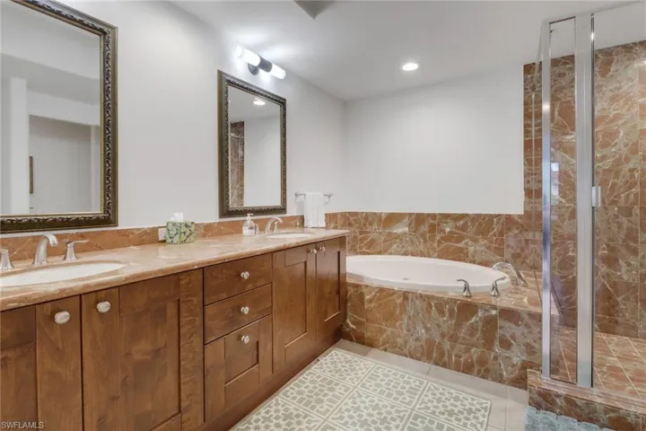 Bathroom featuring tile patterned floors, vanity, and separate shower and tub
