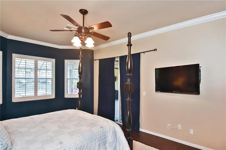 Bedroom featuring ornamental molding, dark wood-style floors, and a ceiling fan