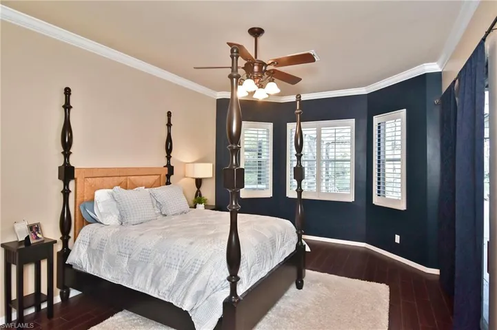 Bedroom featuring dark wood-type flooring, crown molding, and a ceiling fan