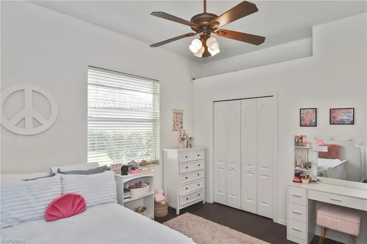 Bedroom featuring ceiling fan, a closet, dark wood finished floors, and an office area