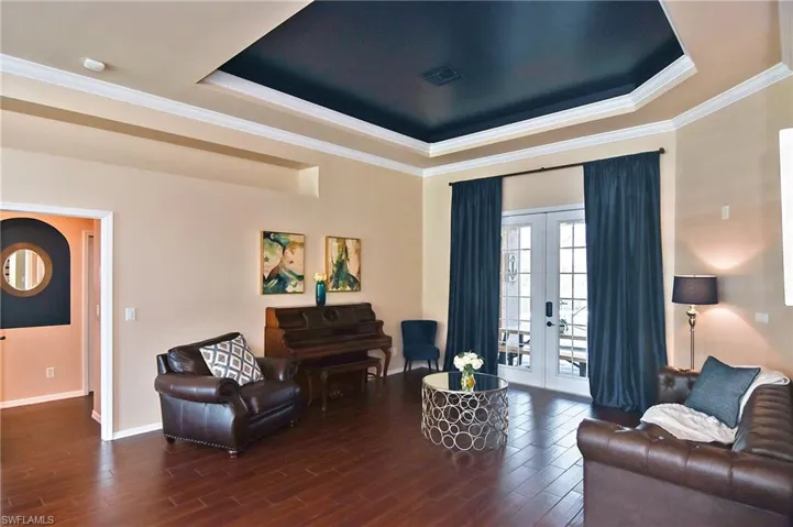 Living room featuring ornamental molding, french doors, wood finished floors, and a tray ceiling