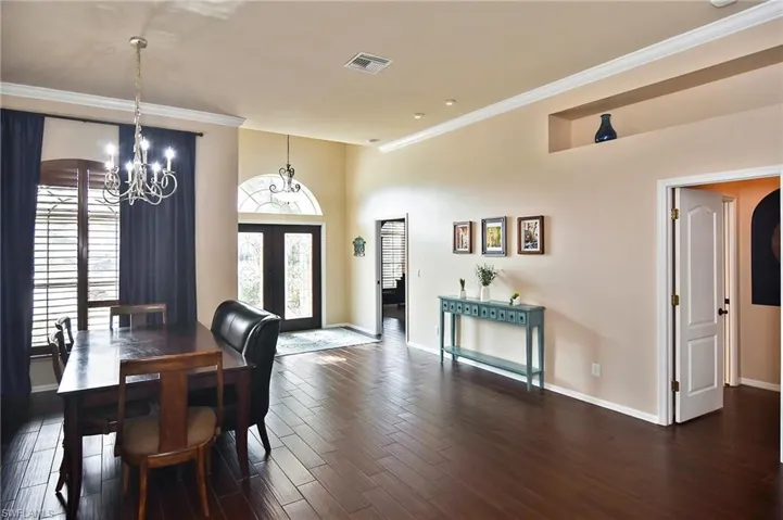Dining area featuring crown molding, wood tiled floors, hanging lights, and french doors