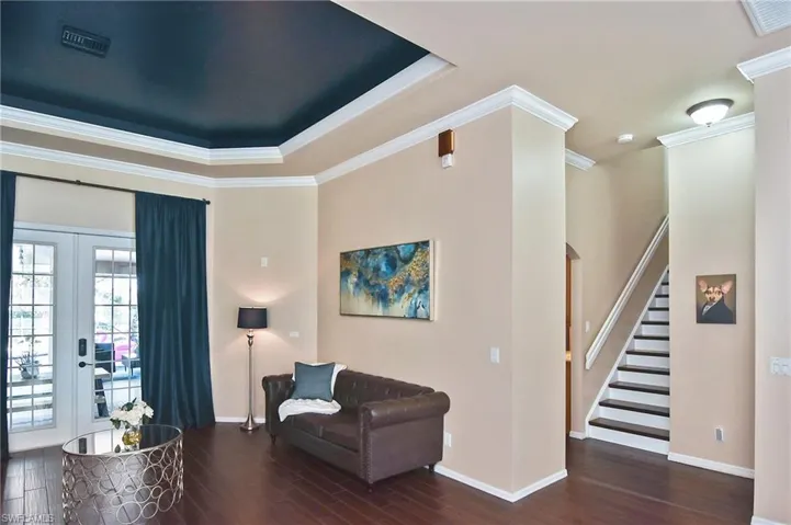 Sitting room with french doors, dark wood-type flooring, crown molding, and a tray ceiling