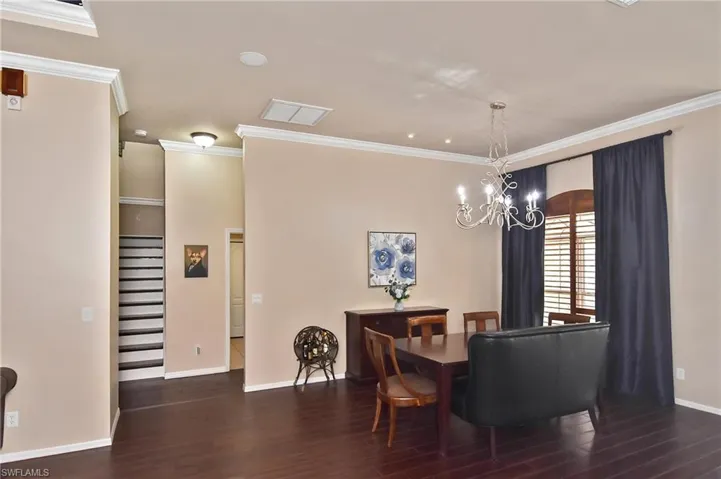 Dining room featuring dark wood-style floors, crown molding, and suspended lighting