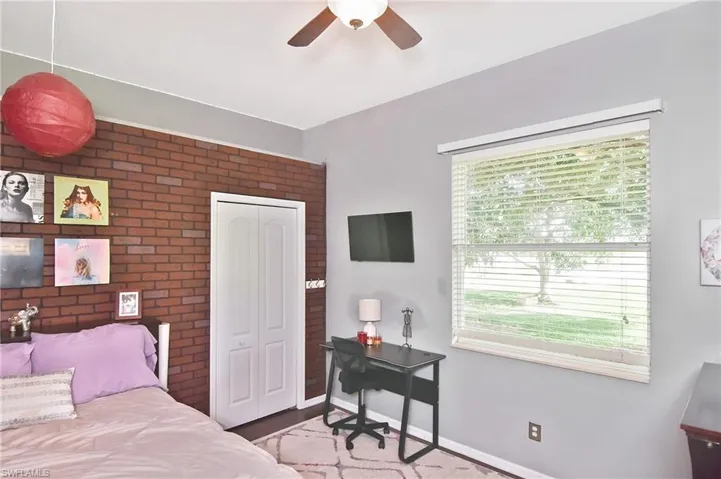 Bedroom featuring brick wall, ceiling fan, and a closet
