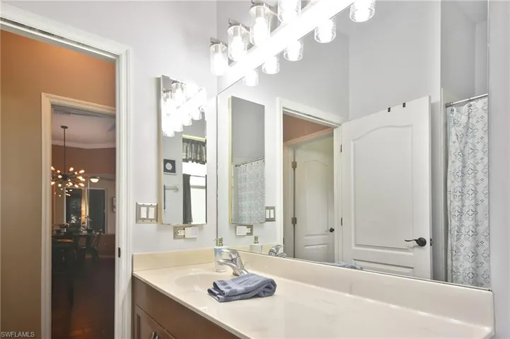 Bathroom with vanity, hanging lights, curtained shower, and wood finished floors