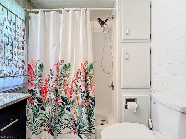 Bathroom featuring a shower with curtain, vanity, and toilet