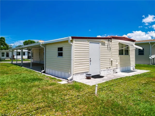 Rear view of house featuring a carport and a yard