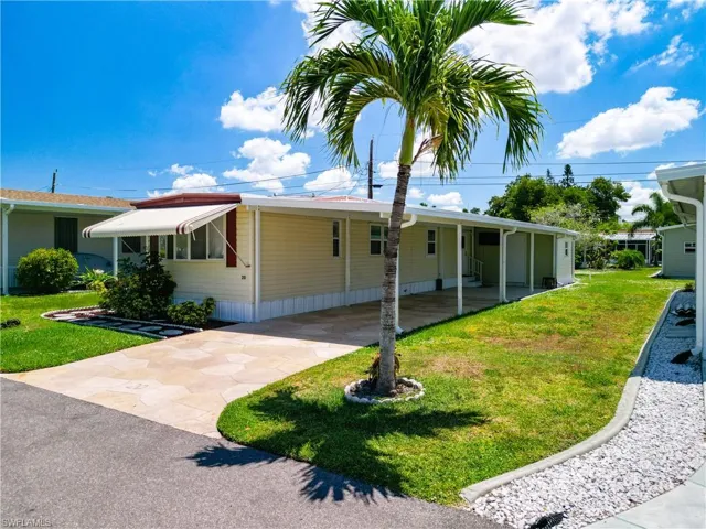 View of front facade featuring a front yard and a carport
