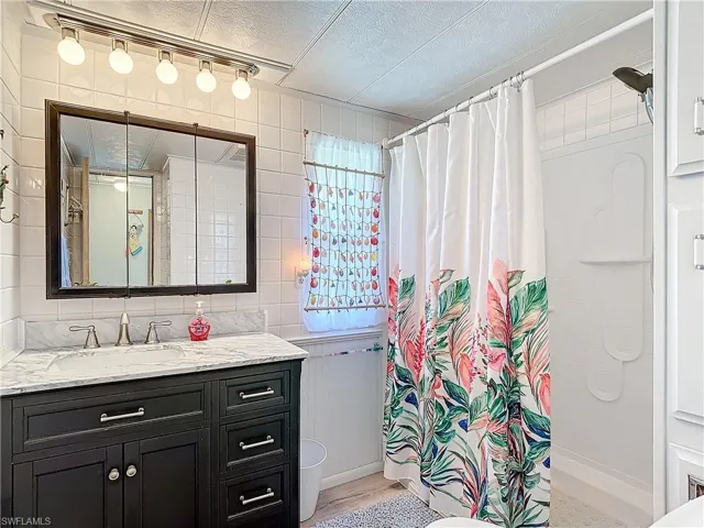 Bathroom featuring tile walls, a textured ceiling, toilet, and large vanity
