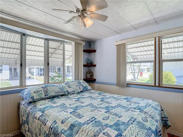 Bedroom with ceiling fan, multiple windows, and access to outside