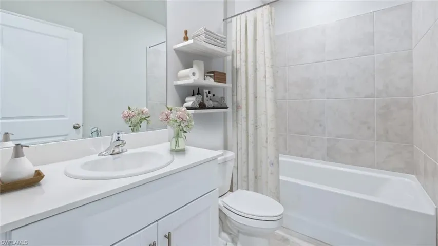 Full bath with toilet, vanity, and shower / bath combination with curtain