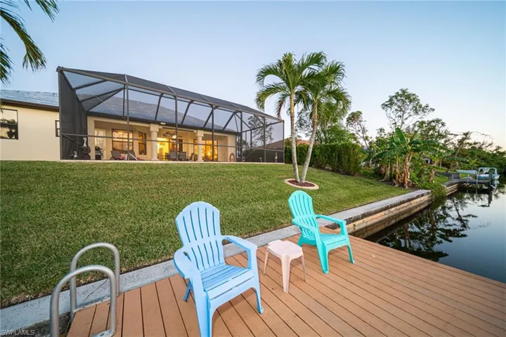 Back of house with a lanai, a sunroom, and a lawn