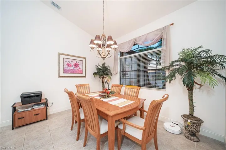 Dining room featuring light tile patterned floors, vaulted ceiling, and a chandelier