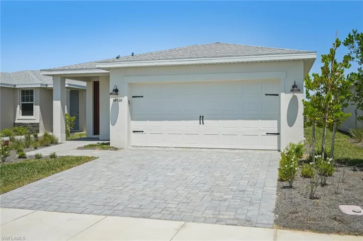 View of front of home with roof with shingles, stucco siding, decorative driveway, and an attached garage