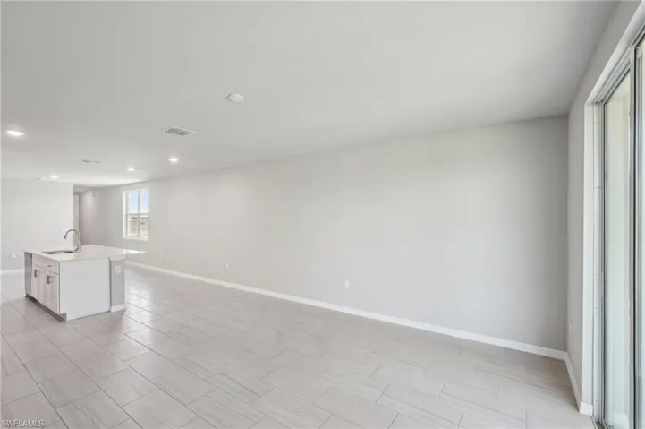 Empty room featuring baseboards, a sink, visible vents, and recessed lighting