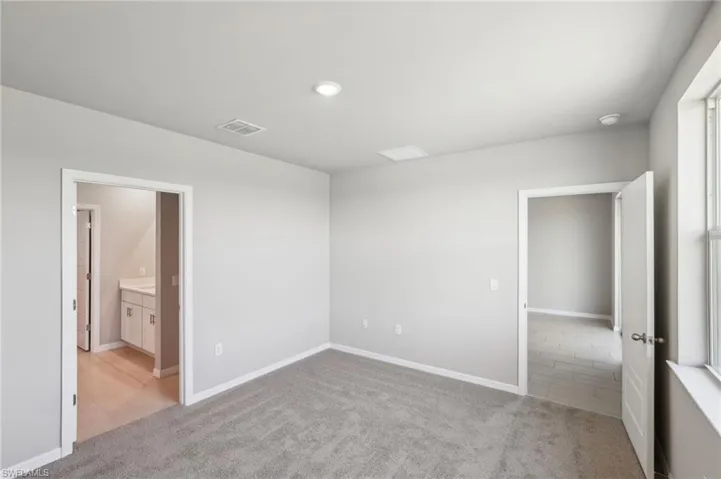 Unfurnished bedroom featuring visible vents, light colored carpet, and baseboards