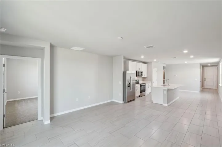 Kitchen with white cabinets, light countertops, a sink, stainless steel appliances, and baseboards