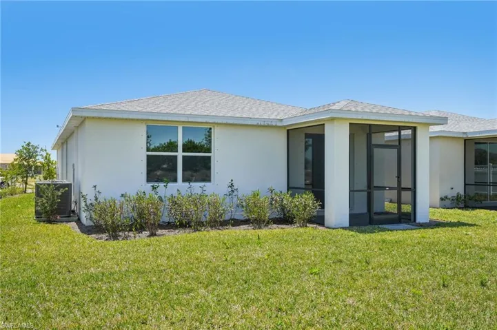 Back of property featuring stucco siding, a lawn, central AC, a sunroom, and a shingled roof