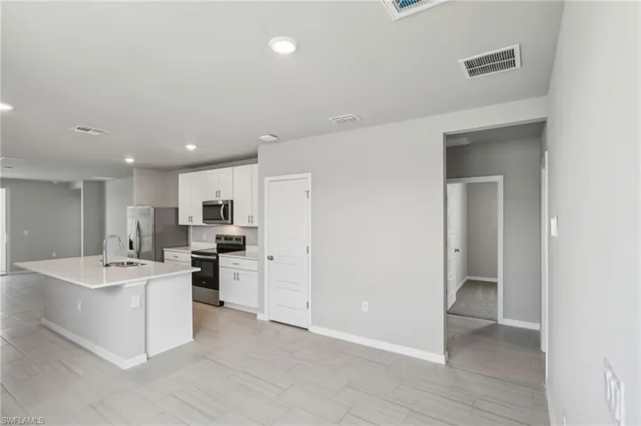 Kitchen with a sink, visible vents, appliances with stainless steel finishes, and white cabinetry