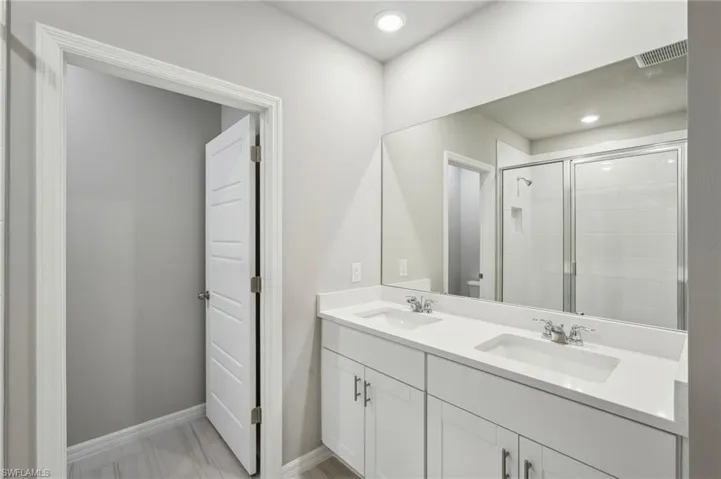 Full bath with a shower stall, a sink, visible vents, and toilet