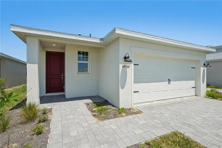 Ranch-style house with driveway, a garage, and stucco siding