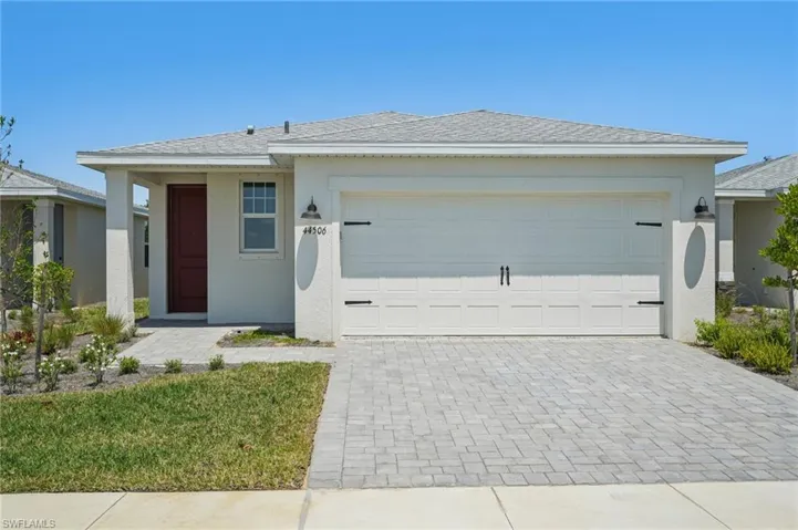 Single story home featuring an attached garage, stucco siding, decorative driveway, and a shingled roof