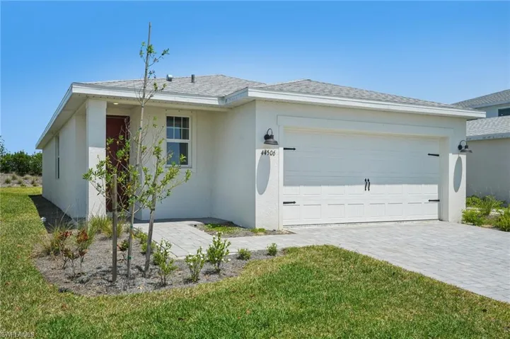 Ranch-style house with a garage, stucco siding, decorative driveway, a front lawn, and a shingled roof